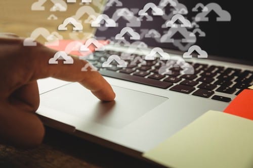 digital composite of hand using laptop with cloud graphics
